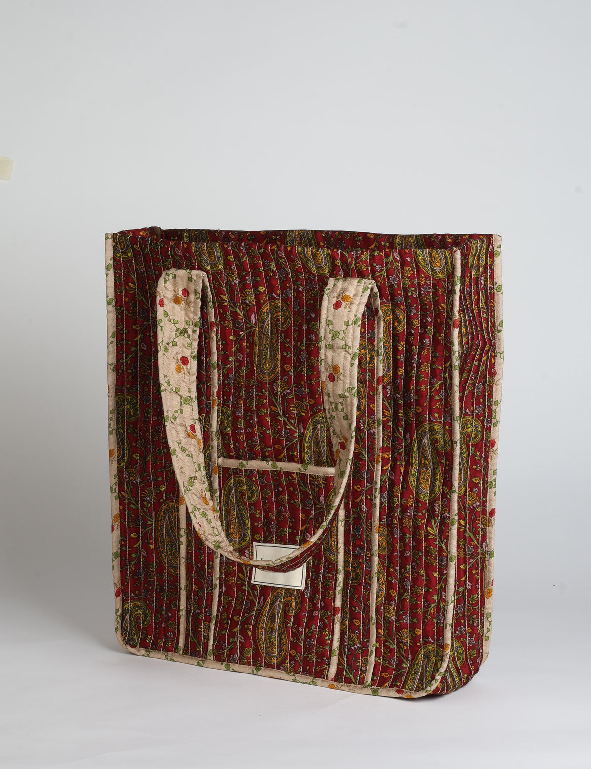 Quilted carry-all tote bag with long shoulder straps, flat base, and external patch pocket.