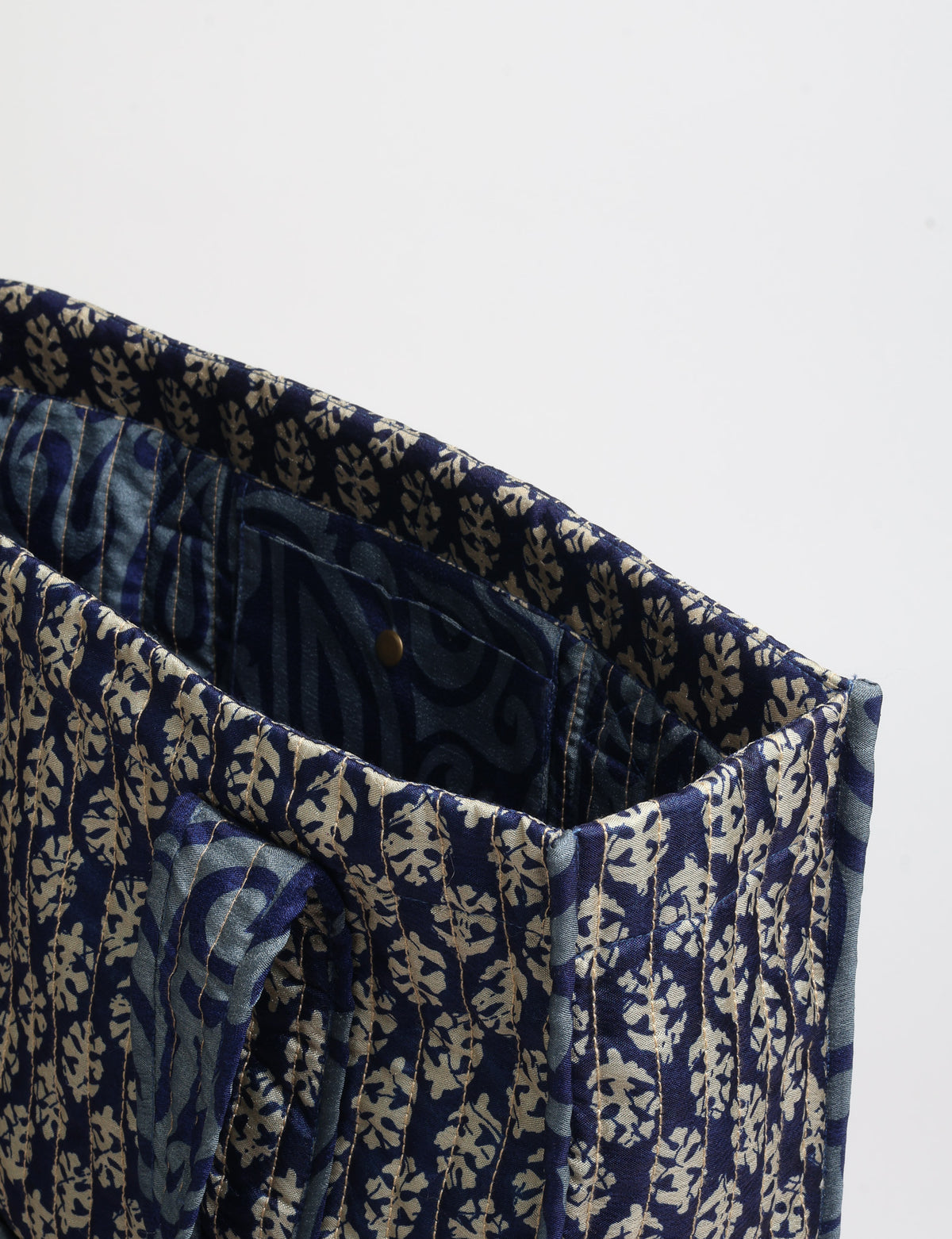 Quilted carry-all tote bag with long shoulder straps, flat base, and external patch pocket.