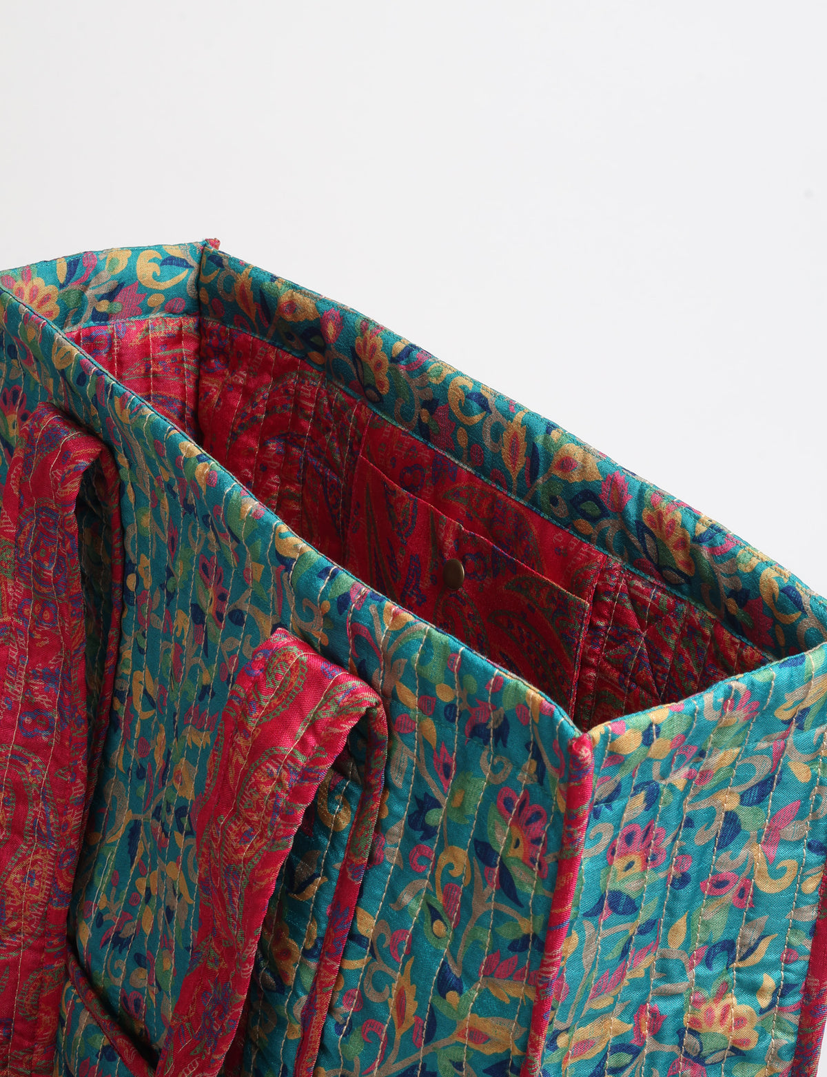 Quilted carry-all tote bag with long shoulder straps, flat base, and external patch pocket.