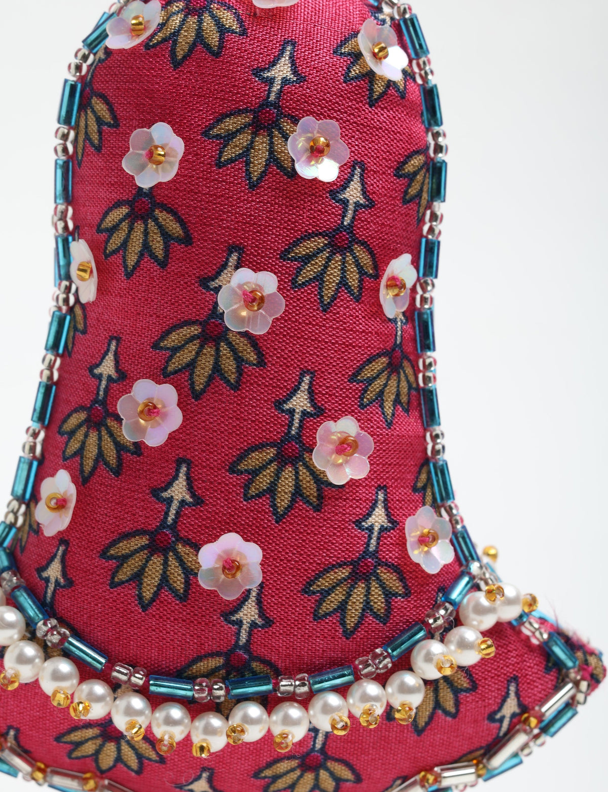 Red fabric bell ornament with gold and navy leaf pattern, decorated with white flower sequins and blue and pearl bead trim