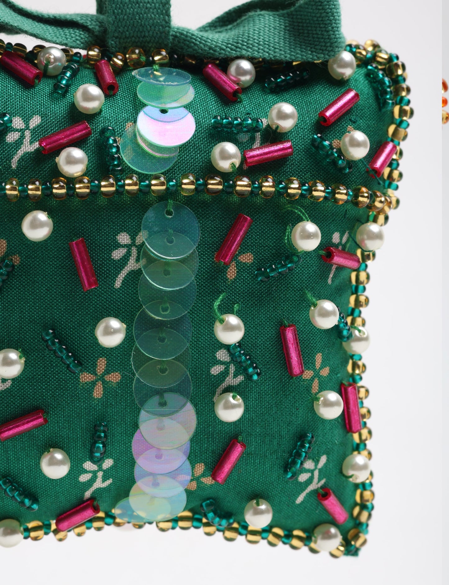 Green fabric gift ornament decorated with pearl beads, red cylindrical beads, iridescent sequins, and gold and green seed