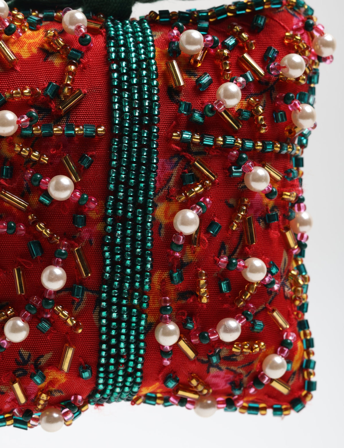 Red fabric ornament decorated with green, gold, pink beads and white pearl-like beads in a detailed pattern