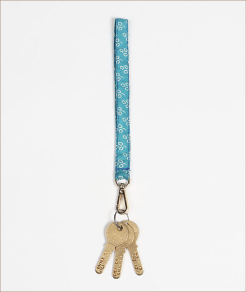 Blue fabric keychain lanyard with white circular pattern and three attached brass keys hanging flat on white background