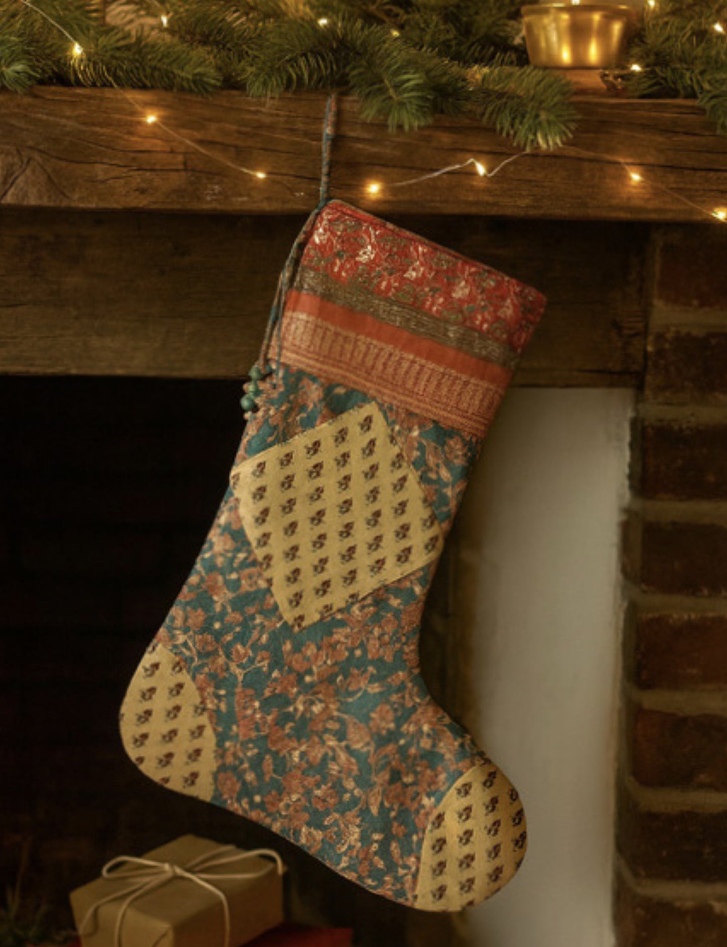 Timeless Christmas stocking made from recycled sari fabric, featuring colorful patchwork, tassel details, and crafted with care in line with circular fashion, upcycling fashion, carbon neutral clothing, and environmentally friendly clothing ideals — a beautiful piece of repurposed clothing and eco clothing for sustainable women’s fashion.