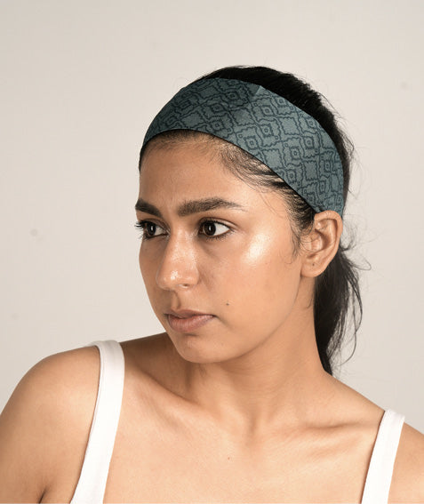 Model wearing a wide dark teal headband with a subtle geometric pattern, styled with a white tank top, front angle