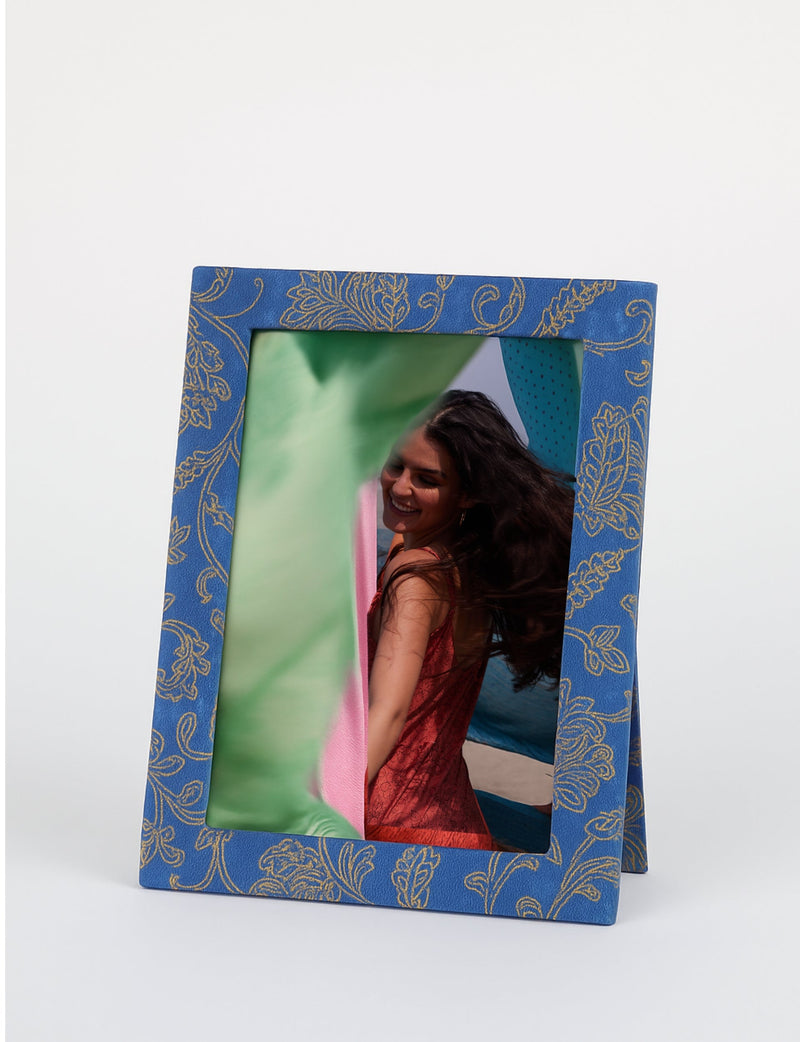 Blue tropical patterned photo frame standing with a smiling woman in a red dress reflected in the glass, front view