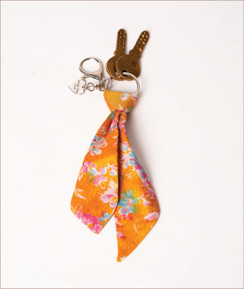 Keychain with small orange fabric tie featuring pink, blue, and white floral pattern, attached to metal ring with two keys