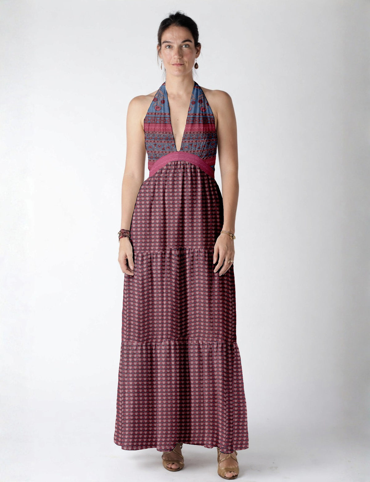Woman wearing a sleeveless maxi tiered dress with pink and blue leaf patterns and a deep V neckline, standing front view