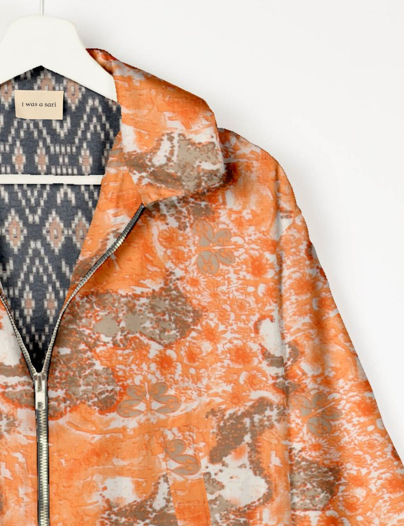 Orange abstract patterned bomber jacket with front zipper, shown on hanger with patterned inner lining