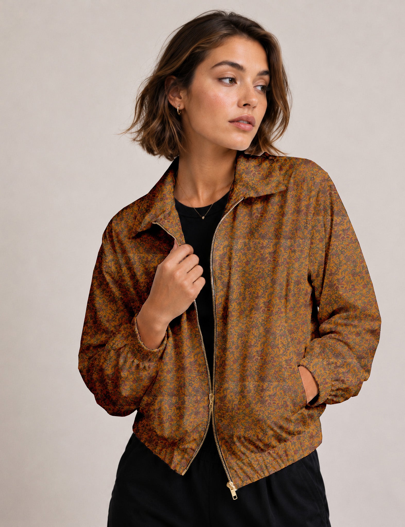 Woman wearing a yellow floral bomber jacket with front zipper, elastic cuffs, and side pockets, shown from front view
