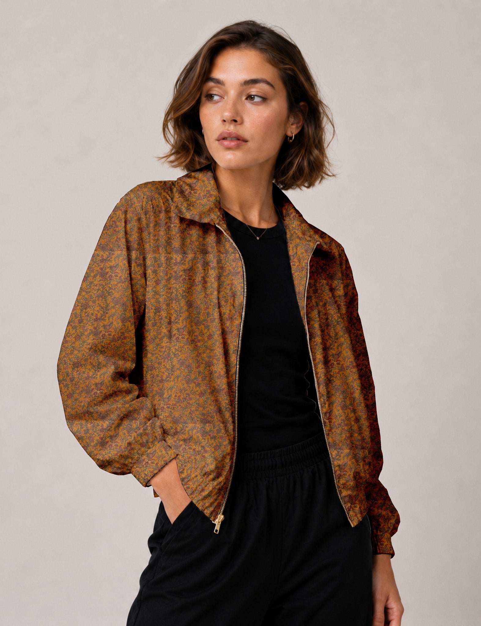 Brown floral bomber jacket with front zipper, elastic cuffs and hem, hanging on white hanger, red floral inner lining visible
