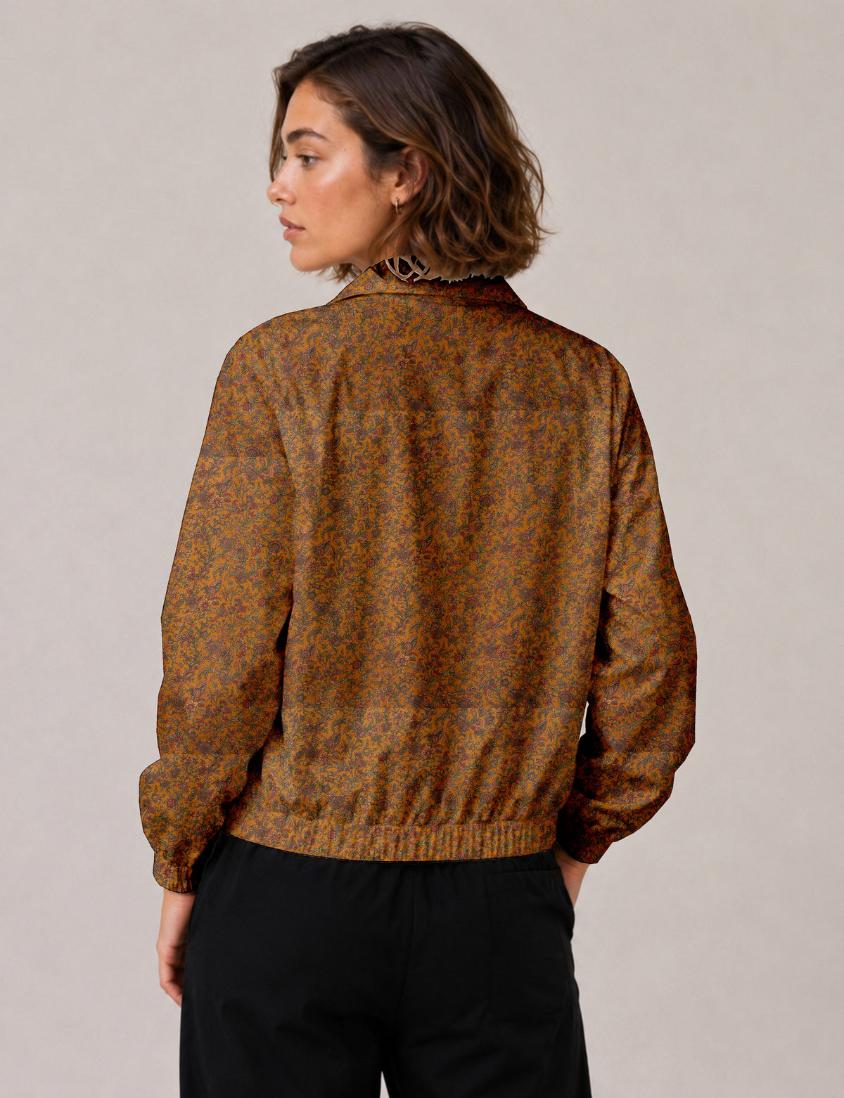 Woman wearing a yellow floral bomber jacket with front zipper, elastic cuffs, and side pockets, shown from front view