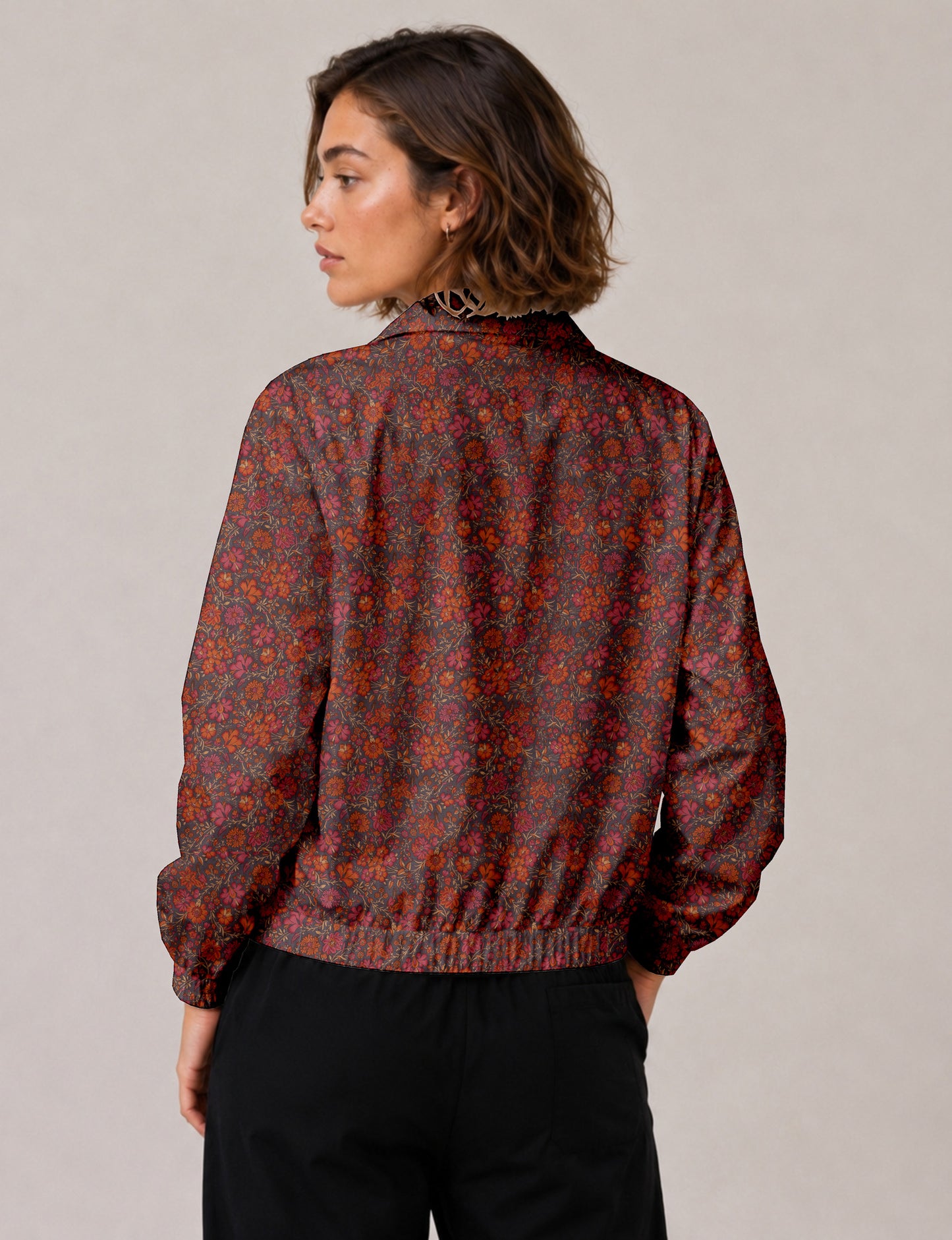 Woman wearing a yellow floral bomber jacket with front zipper, elastic cuffs, and side pockets, shown from front view