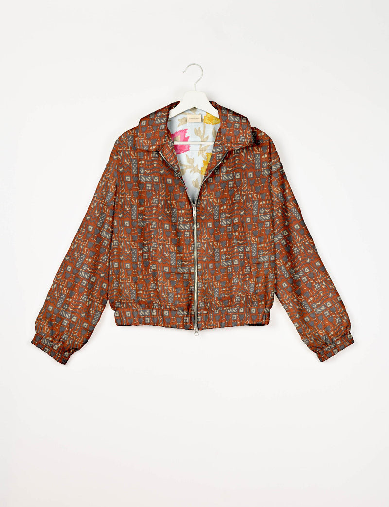 Orange bomber jacket with Indian ethnic geometric pattern, front zipper, collar, and elastic cuffs, shown on hanger front
