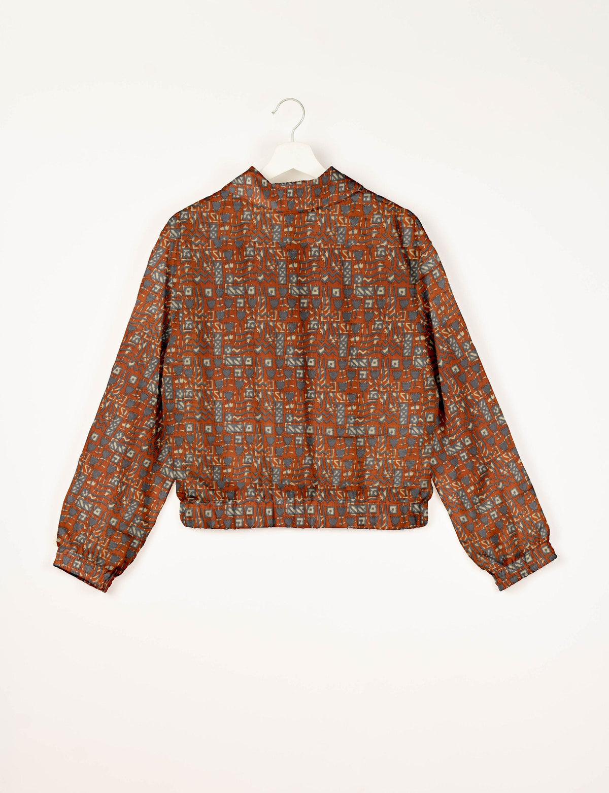 Orange bomber jacket with Indian ethnic geometric pattern in gray and beige, shown from back on white hanger