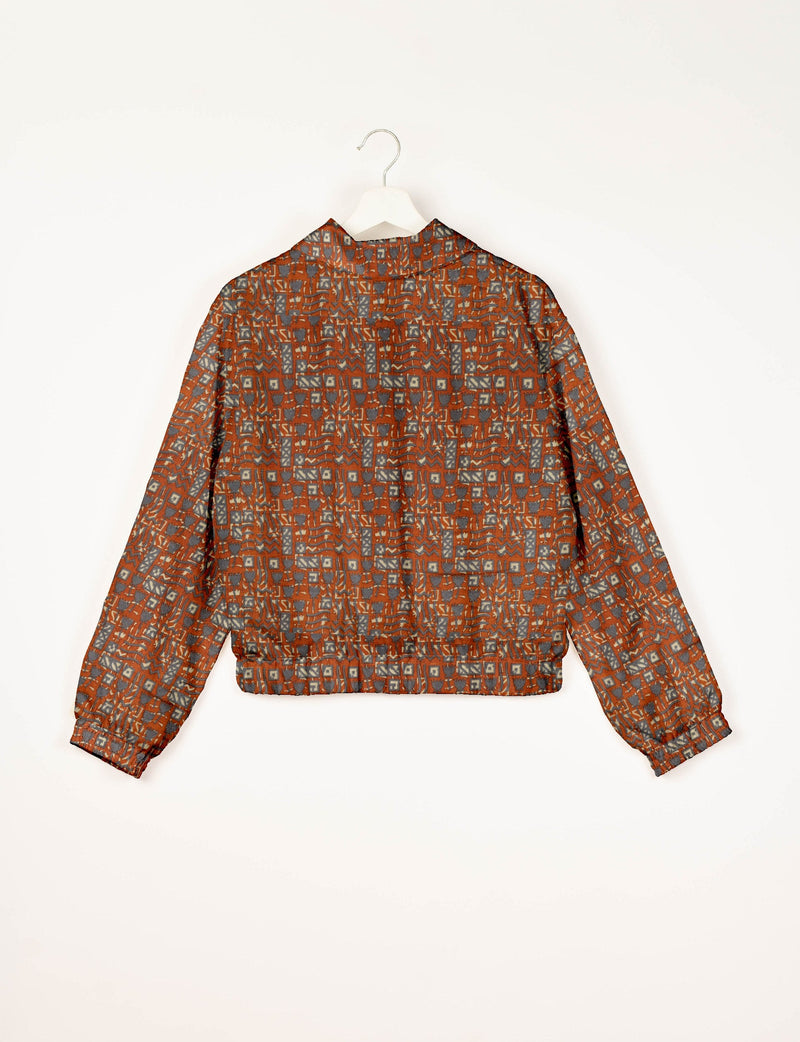 Orange bomber jacket with Indian ethnic geometric pattern in gray and beige, shown from back on white hanger