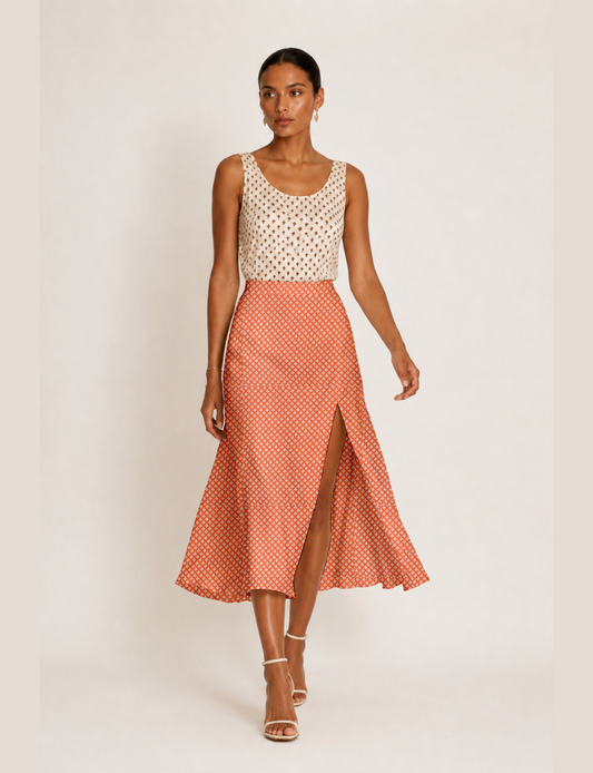 Woman wearing a yellow and black micro patterned A-line skirt with front slit, paired with beige sleeveless top and black