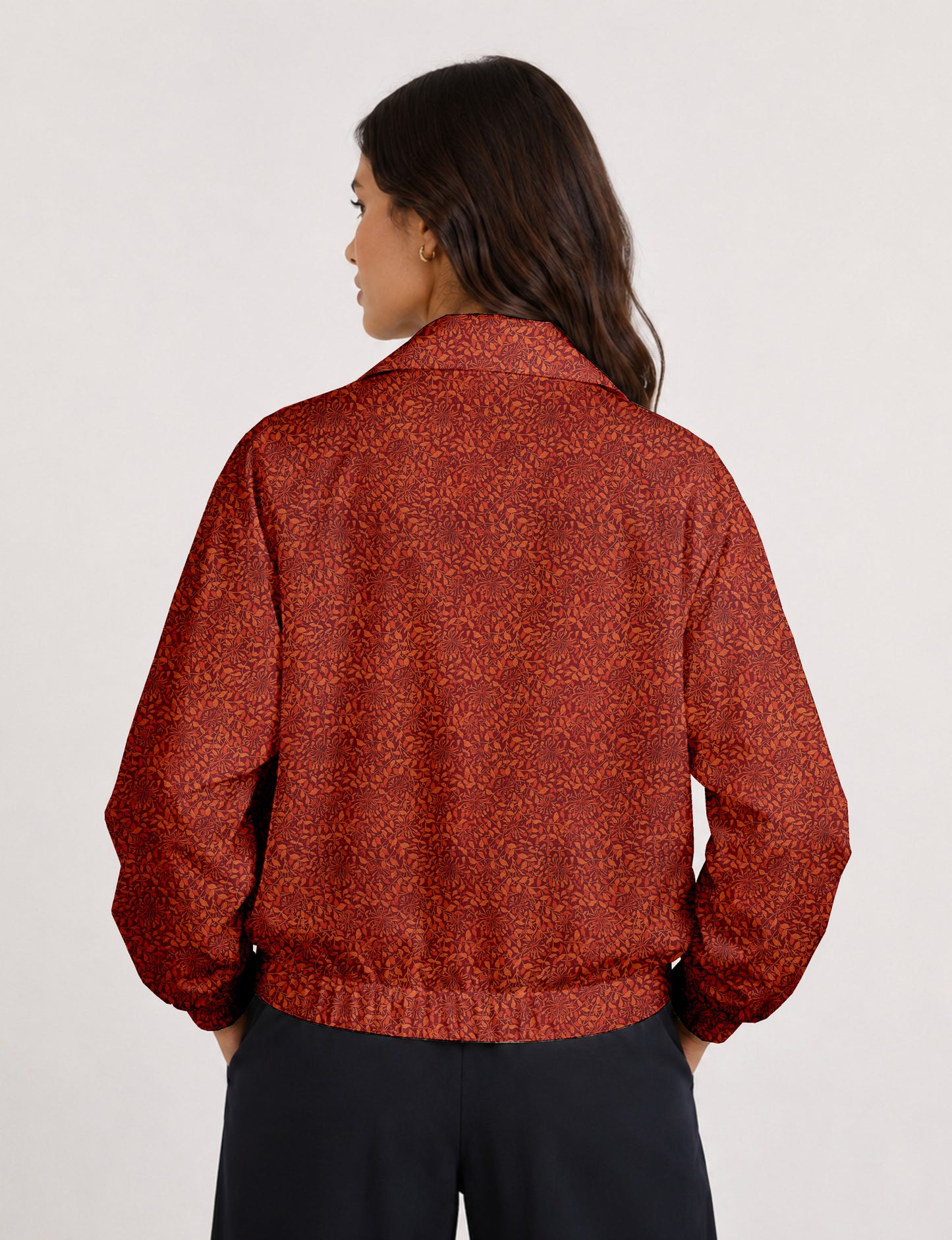 Brown floral bomber jacket with front zipper, elastic cuffs and hem, hanging on white hanger, red floral inner lining visible