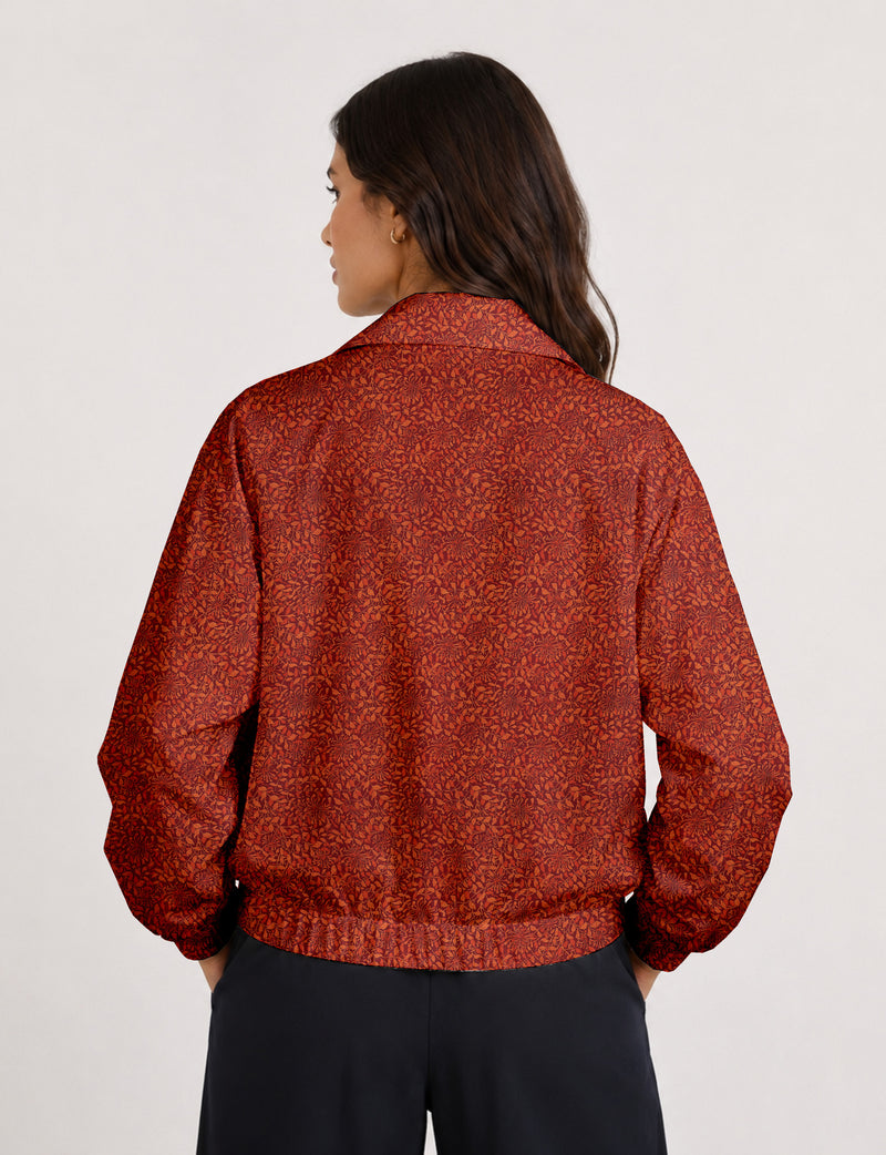 Brown floral bomber jacket with front zipper, elastic cuffs and hem, hanging on white hanger, red floral inner lining visible