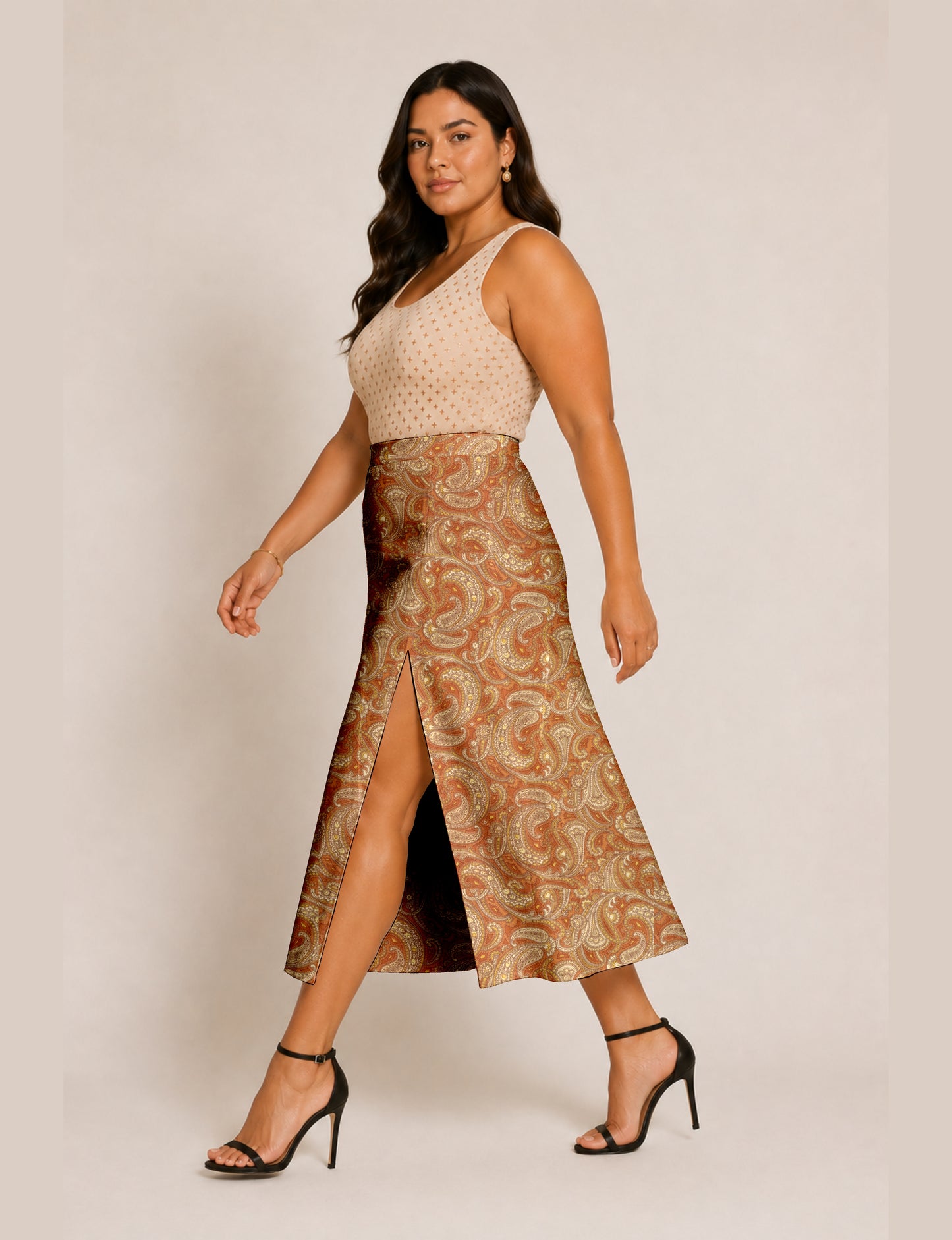 Woman wearing an orange paisley A-line skirt with front slit and black ankle-strap high heels, side view