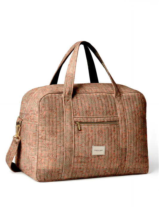 Quilted duffle bag in orange paisley pattern with dual handles, front zip pocket, and "I was a sari" label on front panel
