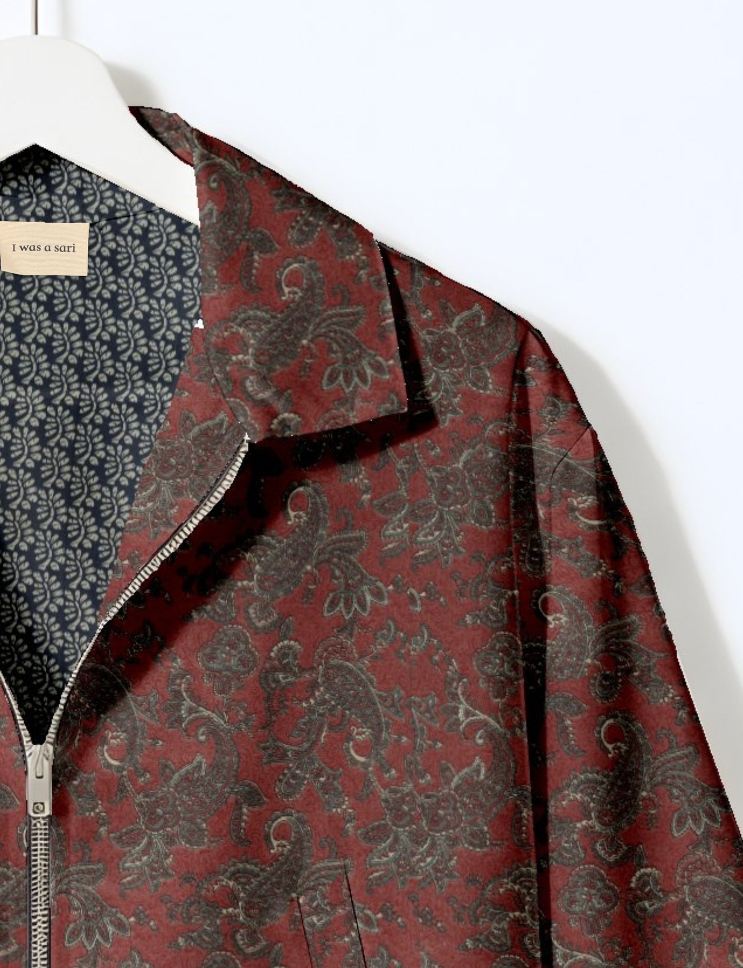 Orange paisley patterned bomber jacket with silver zipper, shown on hanger with navy blue patterned lining and "I was a