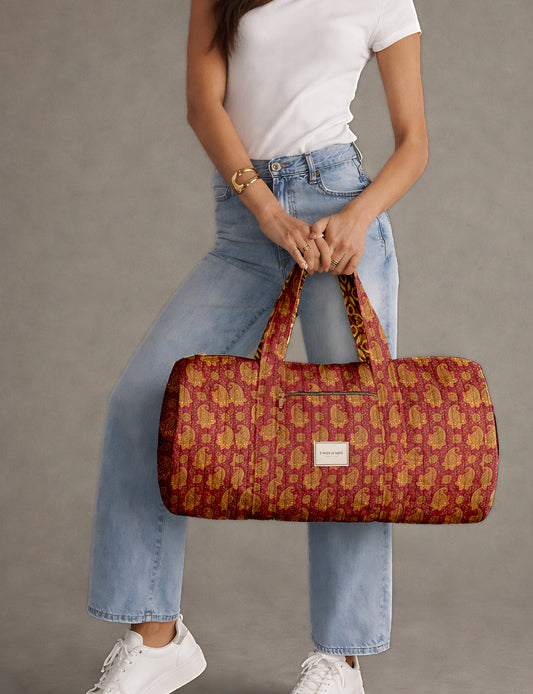 Brown paisley quilted bowling bag with dual handles, front zipper pocket, and "I was a sari" label on front side