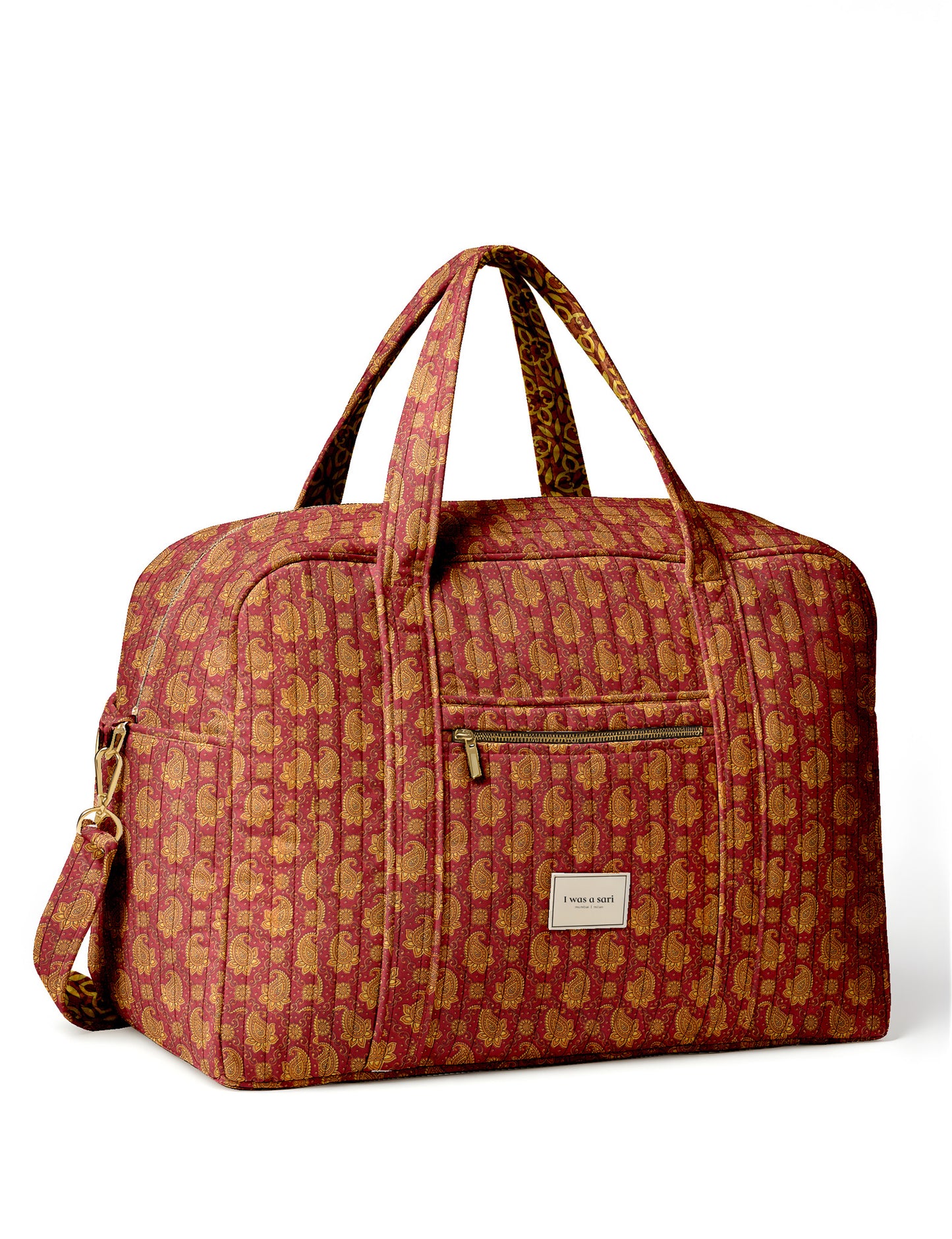 Brown quilted duffle bag with paisley pattern, front zip pocket, dual handles, and label reading "I was a sari"