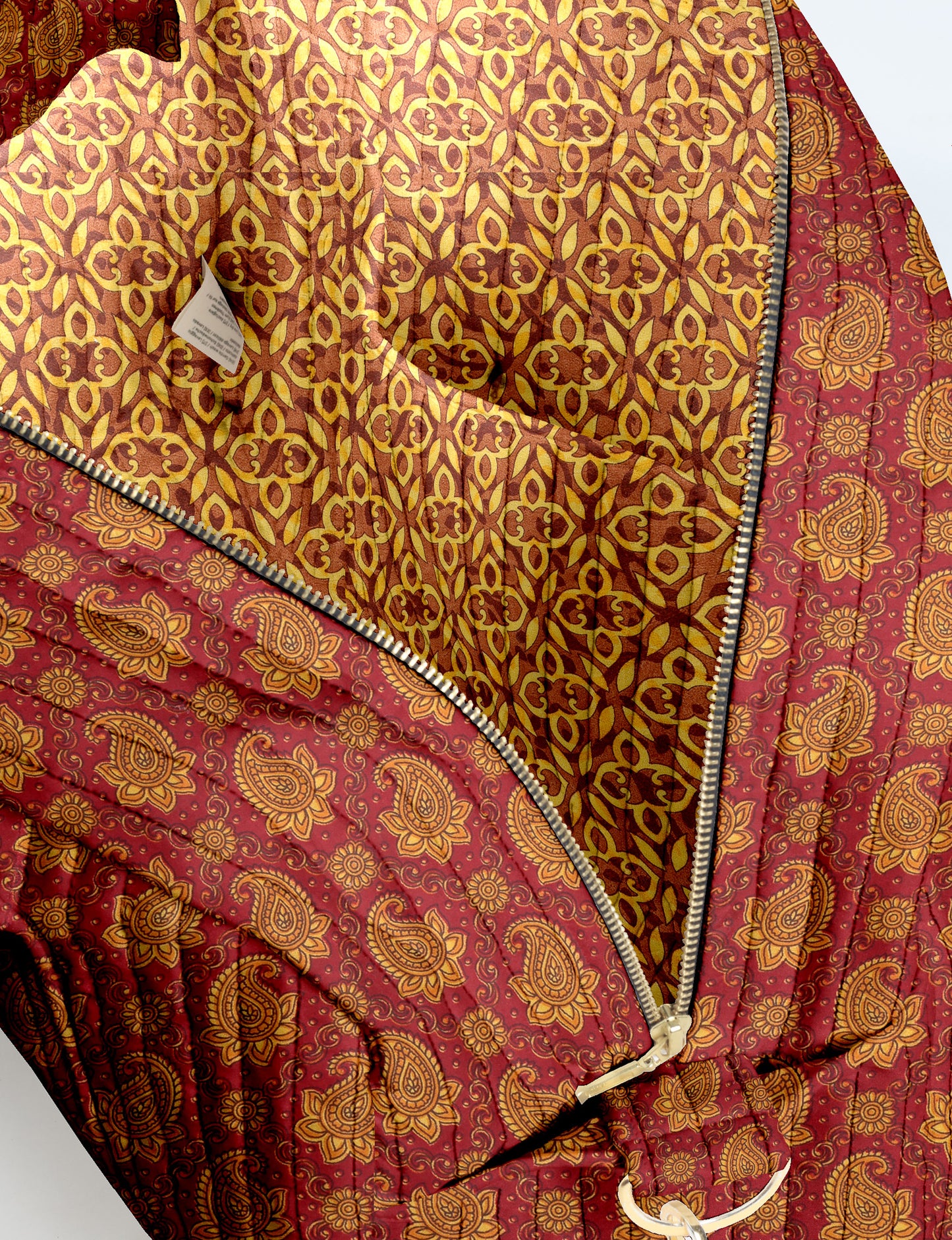 Brown quilted duffle bag with paisley pattern, front zip pocket, dual handles, and label reading "I was a sari"