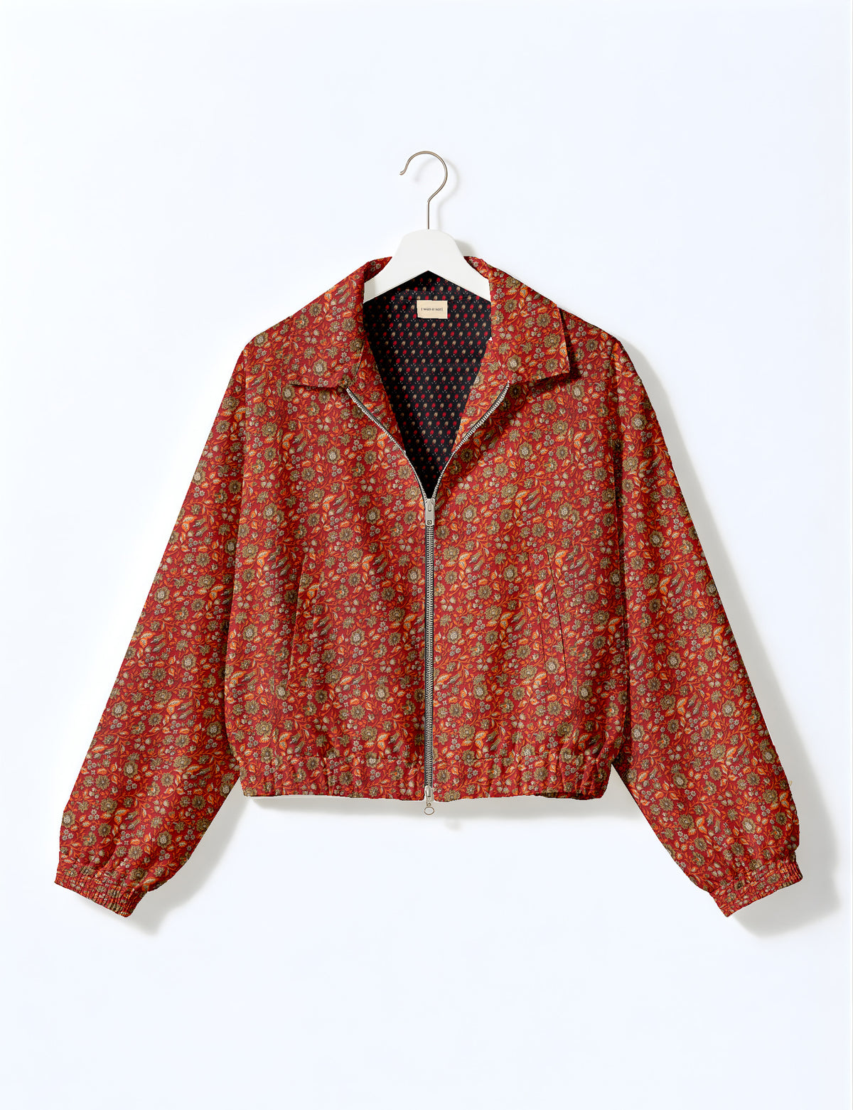 Brown floral bomber jacket with front zipper, elastic cuffs and hem, hanging on white hanger, red floral inner lining visible