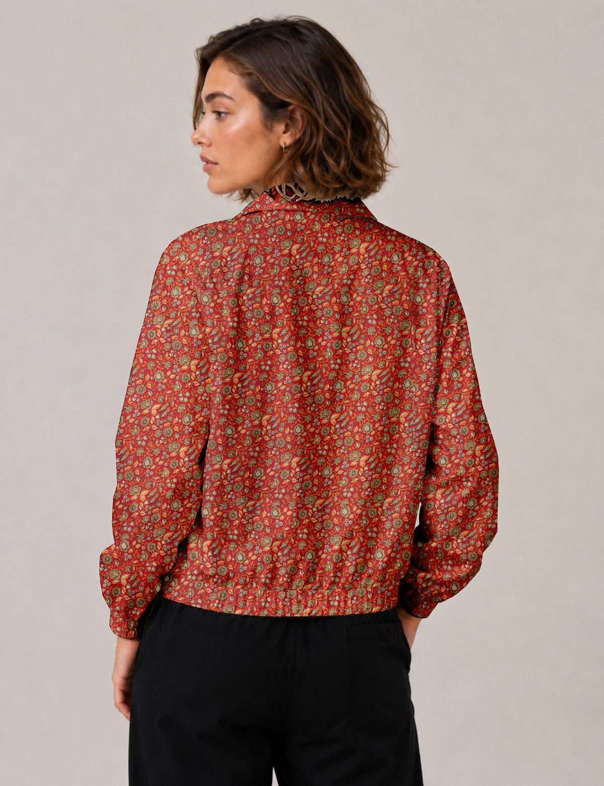 Woman wearing a yellow floral bomber jacket with front zipper, elastic cuffs, and side pockets, shown from front view