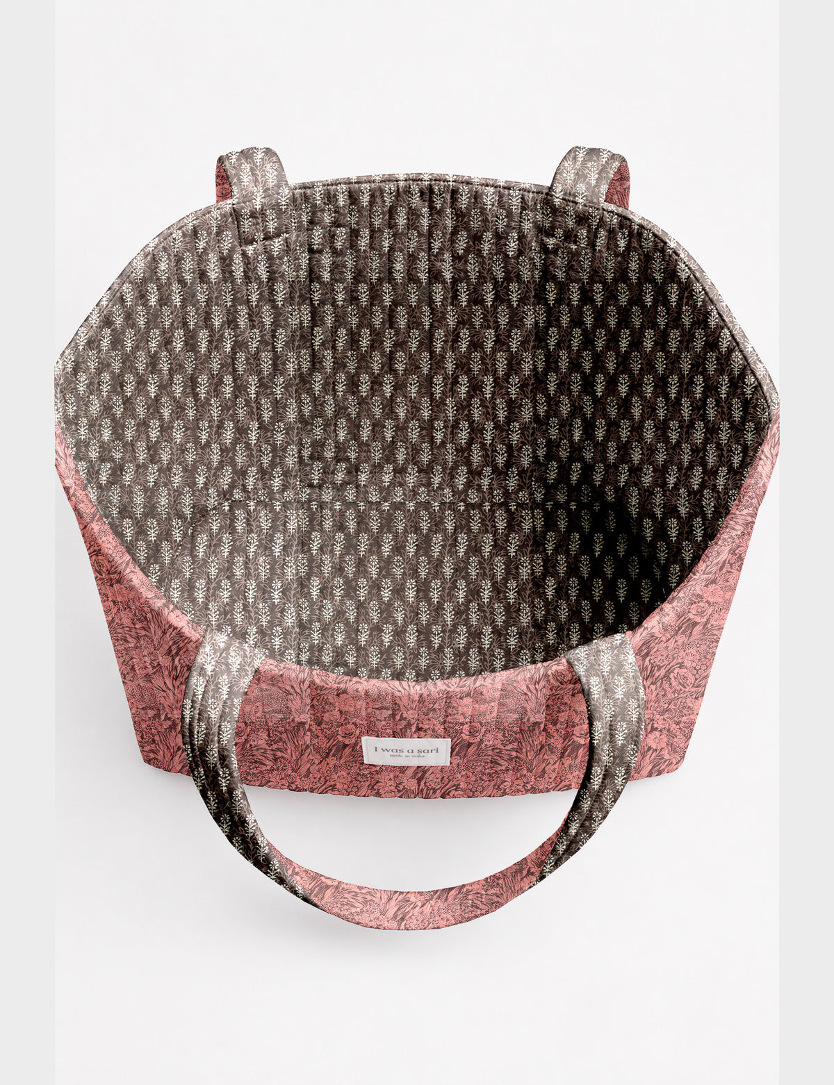 Quilted beach bag with yellow tropical exterior and red patterned interior, shown from top view with handles visible