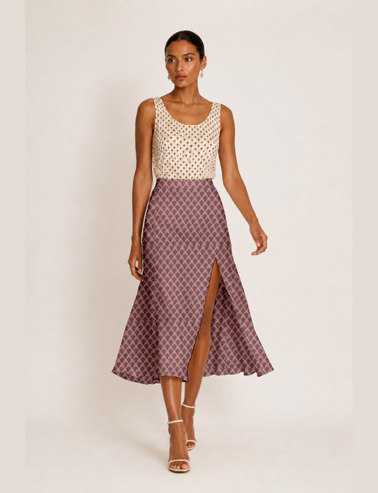 Woman wearing a yellow and black micro patterned A-line skirt with front slit, paired with beige sleeveless top and black