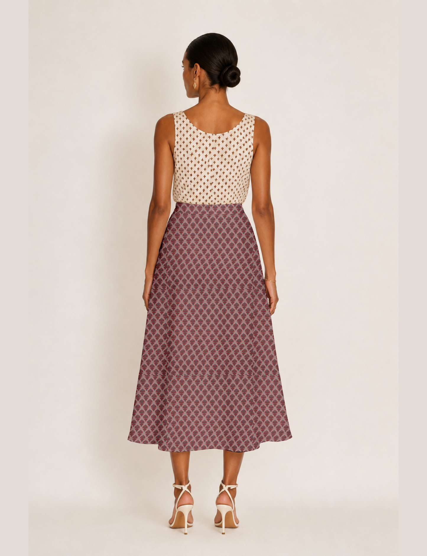 Woman wearing a yellow and black micro patterned A-line skirt with front slit, paired with beige sleeveless top and black