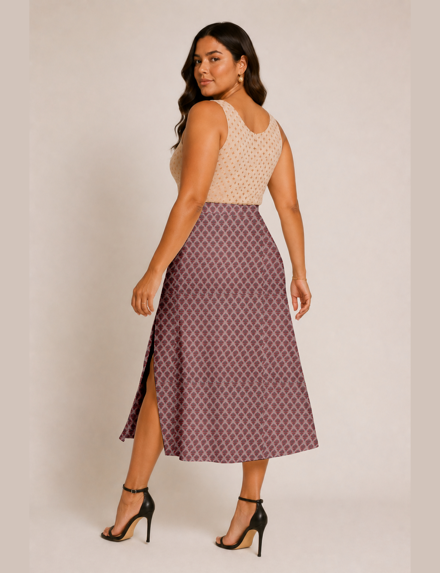 Woman wearing a yellow and black micro patterned A-line skirt with front slit, paired with beige sleeveless top and black