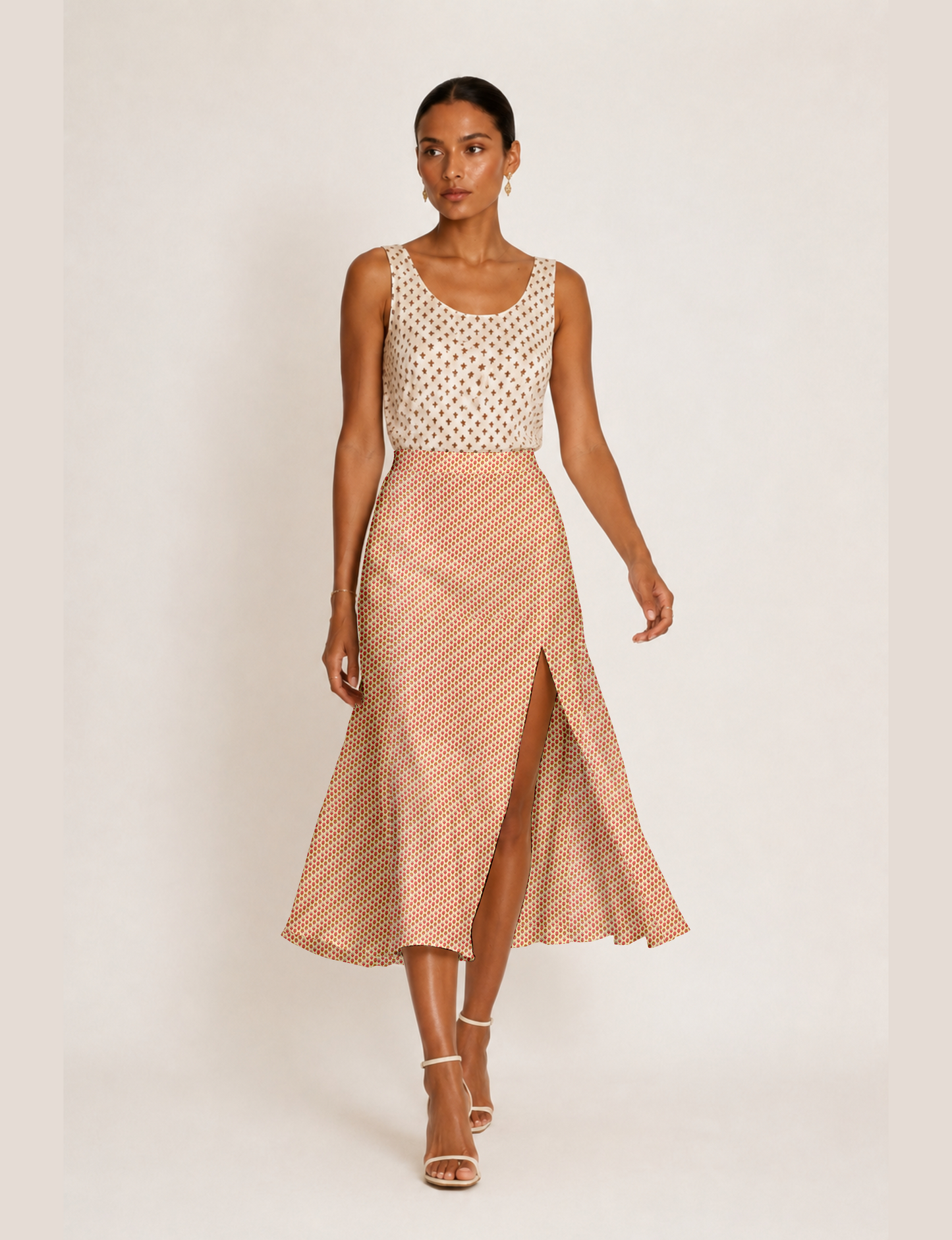Woman wearing a yellow and black micro patterned A-line skirt with front slit, paired with beige sleeveless top and black
