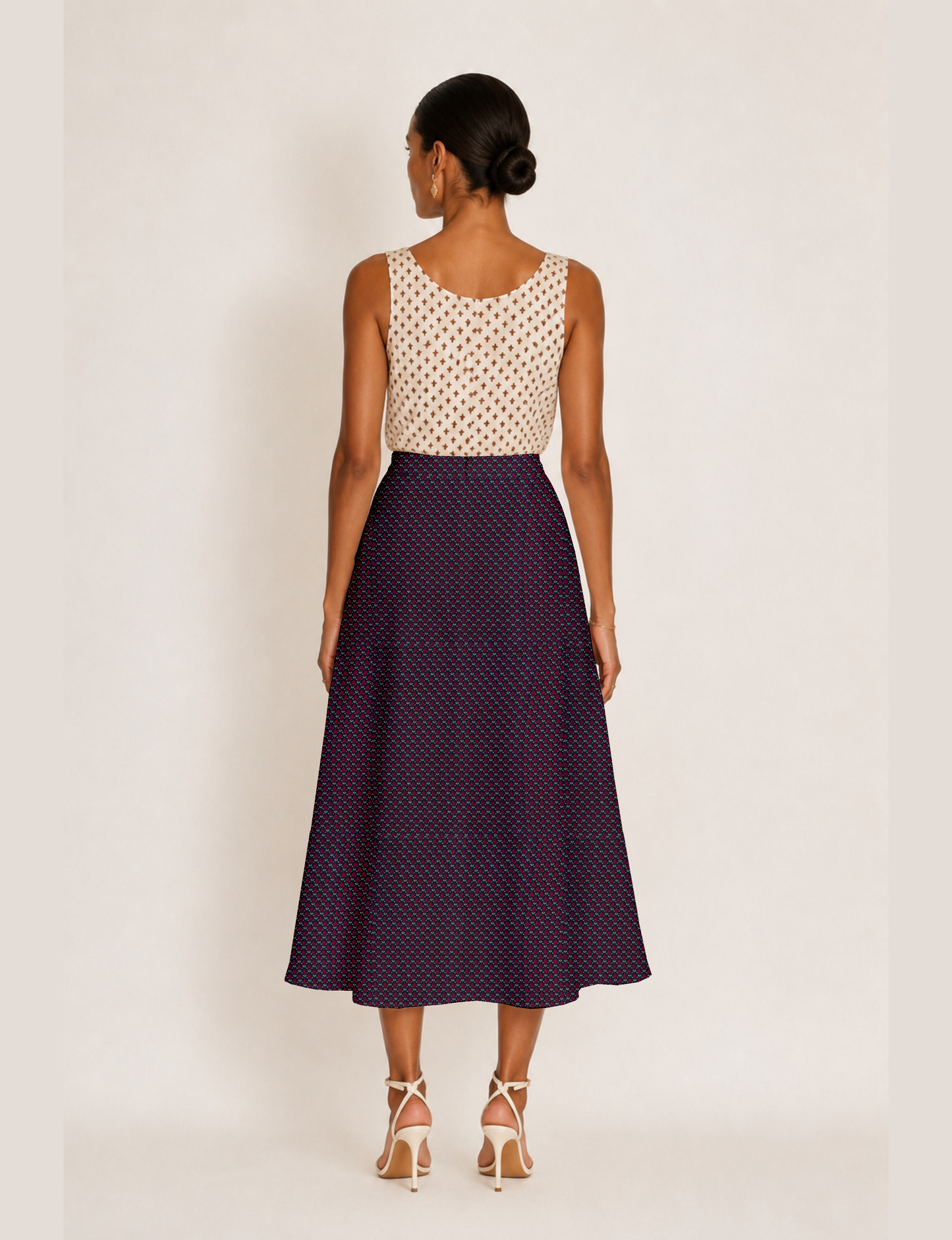 Woman wearing a yellow and black micro patterned A-line skirt with front slit, paired with beige sleeveless top and black