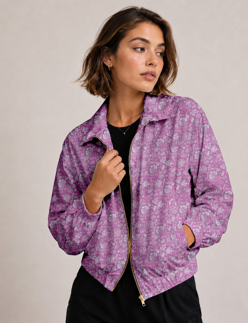 Woman wearing a yellow floral bomber jacket with front zipper, elastic cuffs, and side pockets, shown from front view