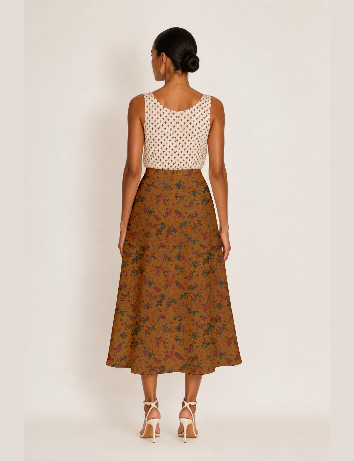 Woman wearing a yellow and navy blue A-line skirt with a slit and a sleeveless beige top with brown micro print