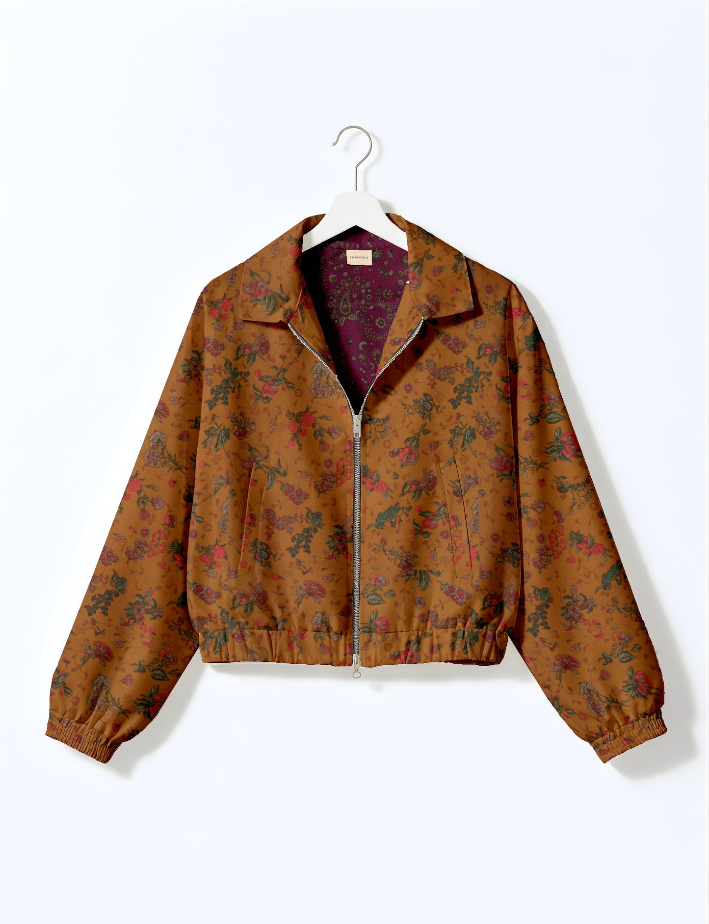 Yellow bomber jacket with micro geometric pattern, silver front zipper, elastic cuffs, and blue floral inner lining, hanging