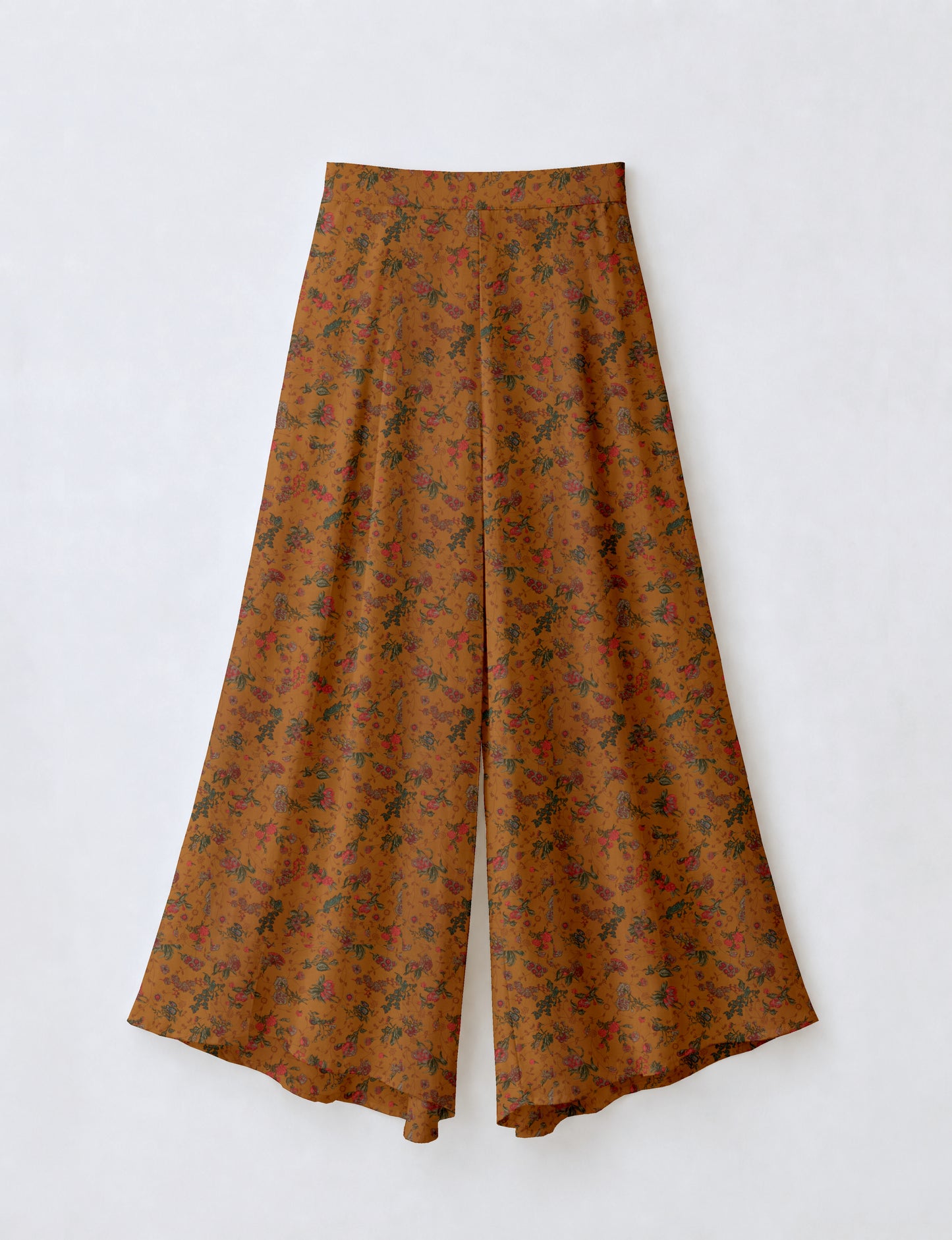 Woman wearing blue wide leg palazzo trousers with black and brown floral print, paired with brown sleeveless top and white