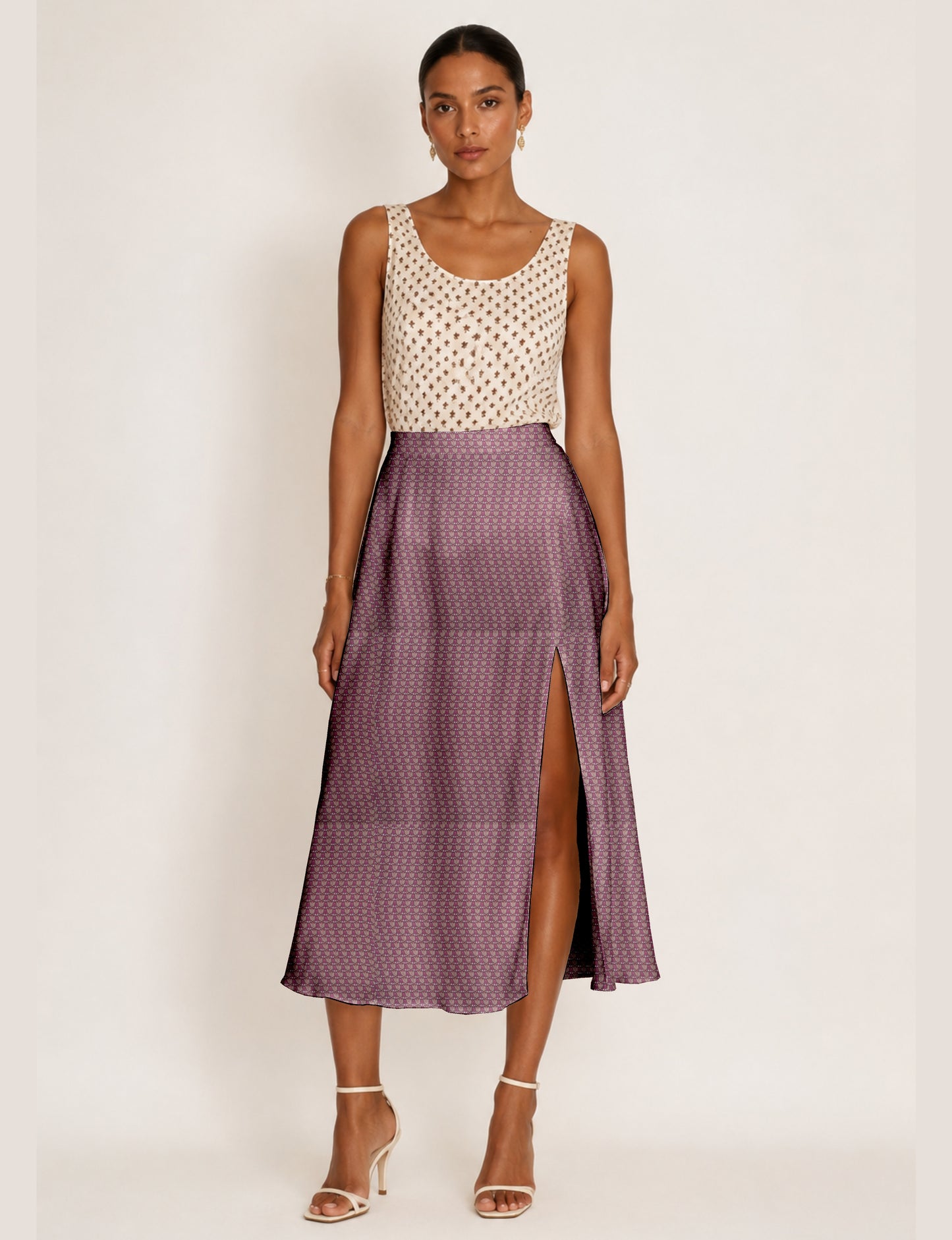 Woman wearing a yellow and black micro patterned A-line skirt with front slit, paired with beige sleeveless top and black