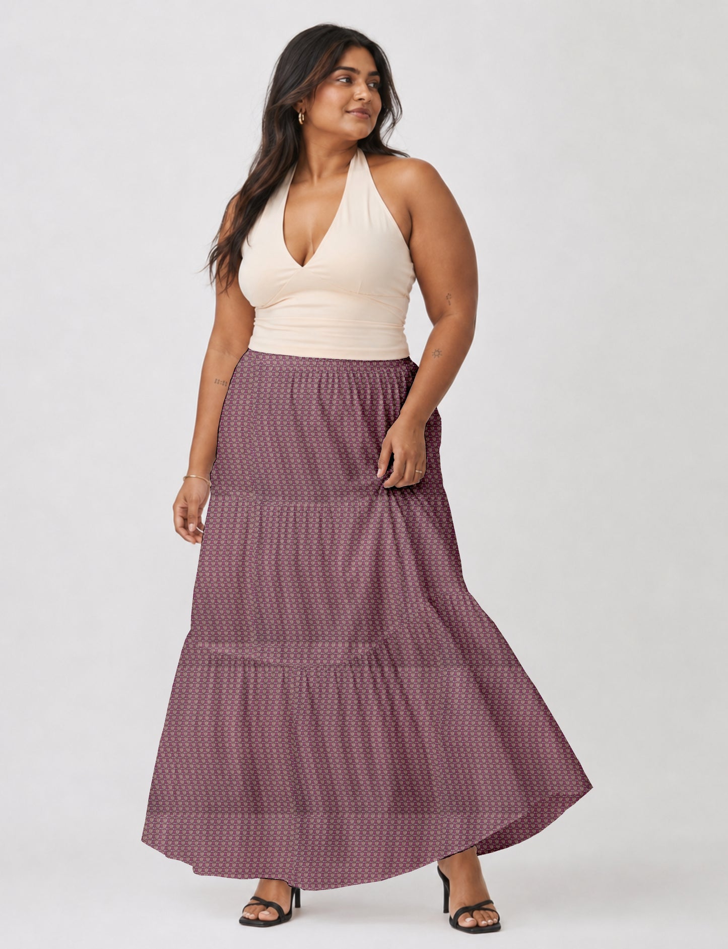 Woman wearing a yellow midi tiered skirt with a small geometric pattern, paired with a beige strapless top and white heels