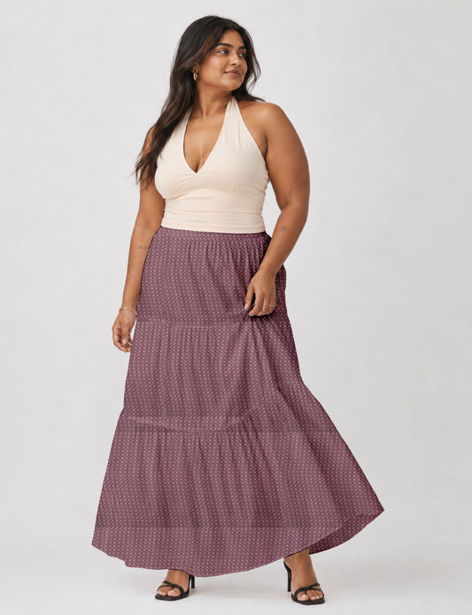 Woman wearing a yellow midi tiered skirt with a small geometric pattern, paired with a beige strapless top and white heels