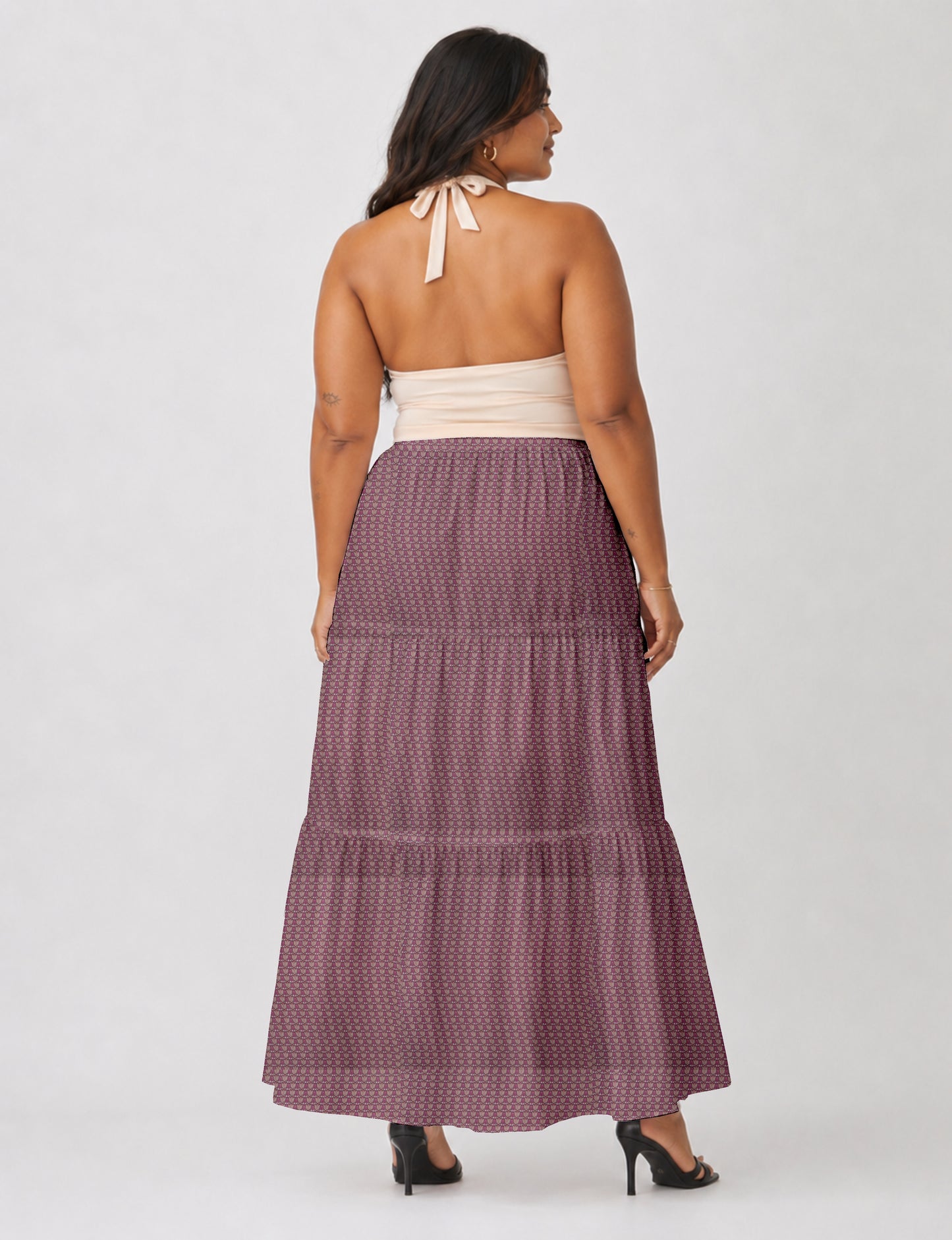 Woman wearing a yellow midi tiered skirt with a small geometric pattern, shown from the back, paired with beige top and