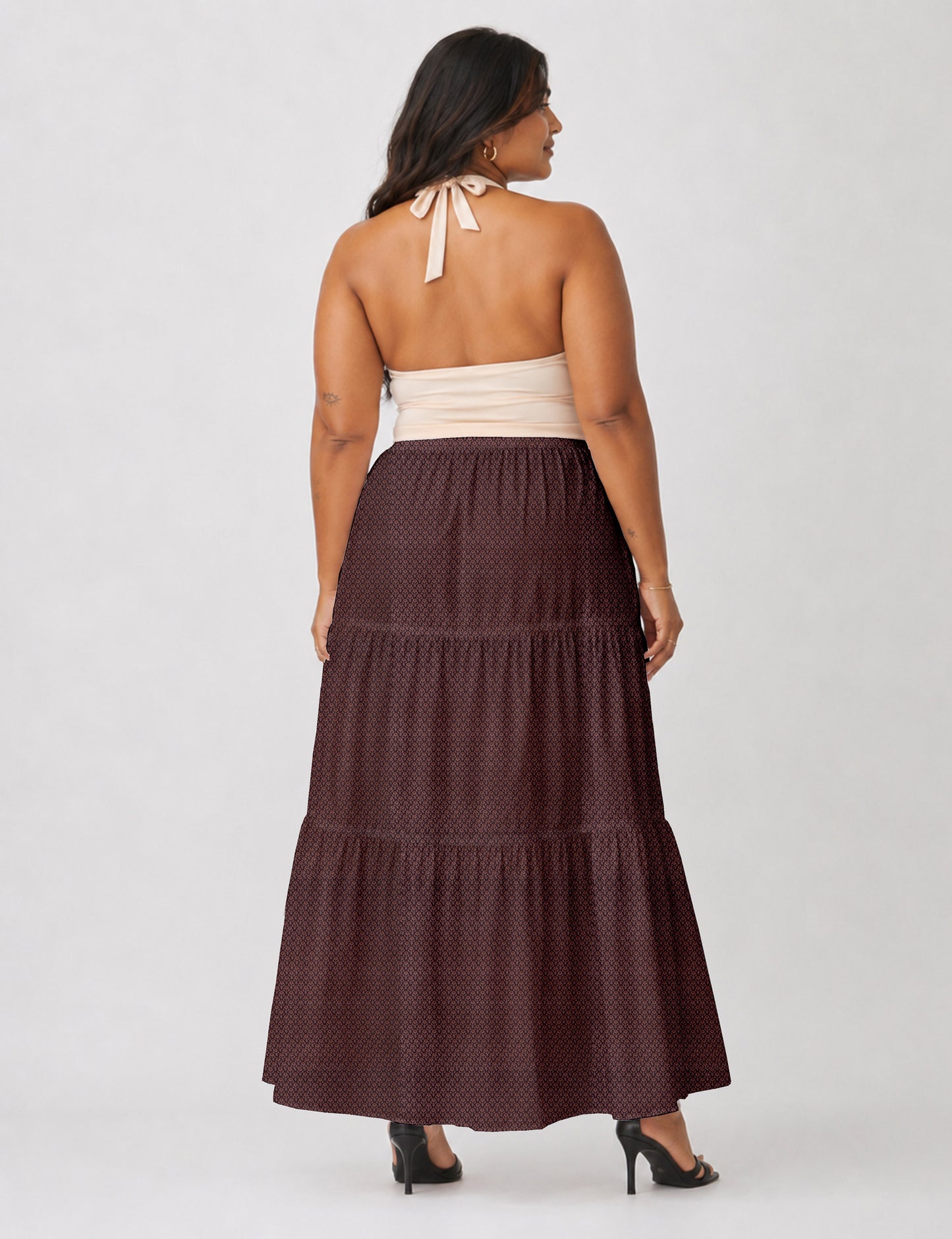 Woman wearing a yellow midi tiered skirt with a small geometric pattern, paired with a beige strapless top and white heels