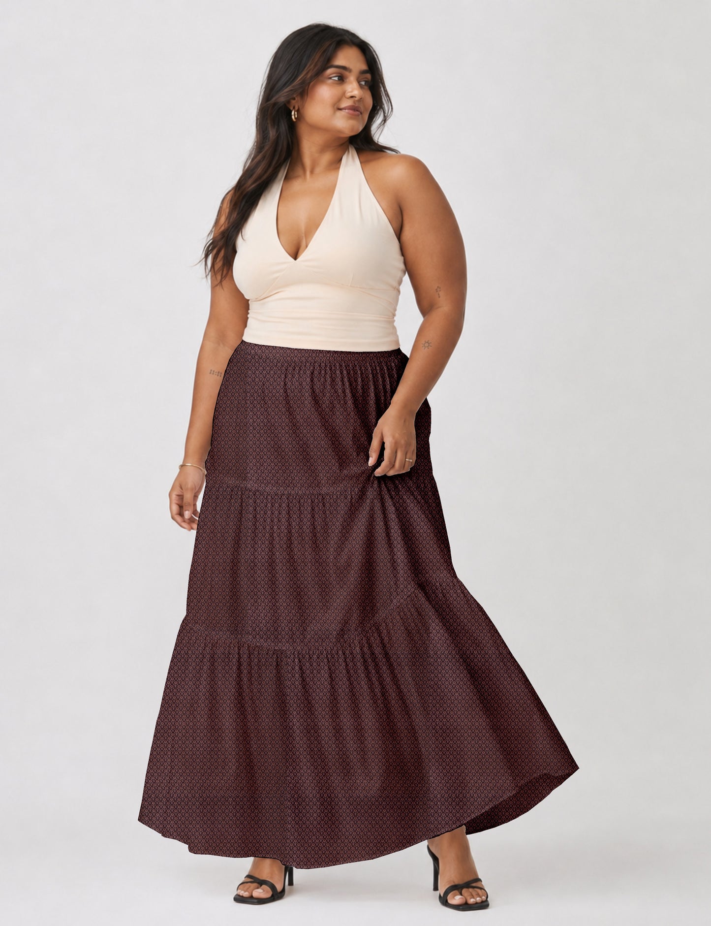 Woman wearing a yellow midi tiered skirt with a small geometric pattern, shown from the back, paired with beige top and