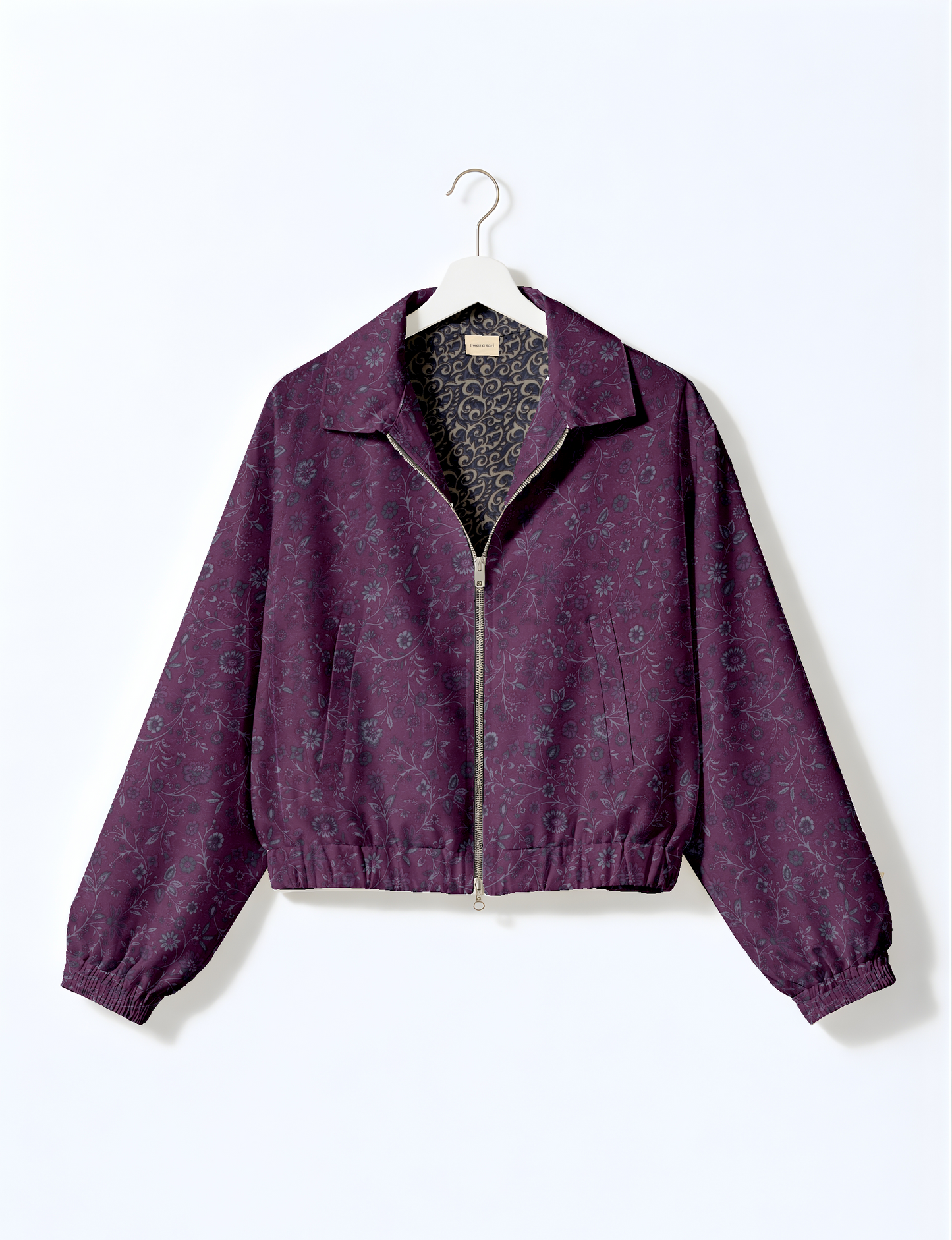 Women's cropped bomber jacket with twin metallic front zippers, welt pockets, elasticated hem and cuffs, and contrast sari print lining.