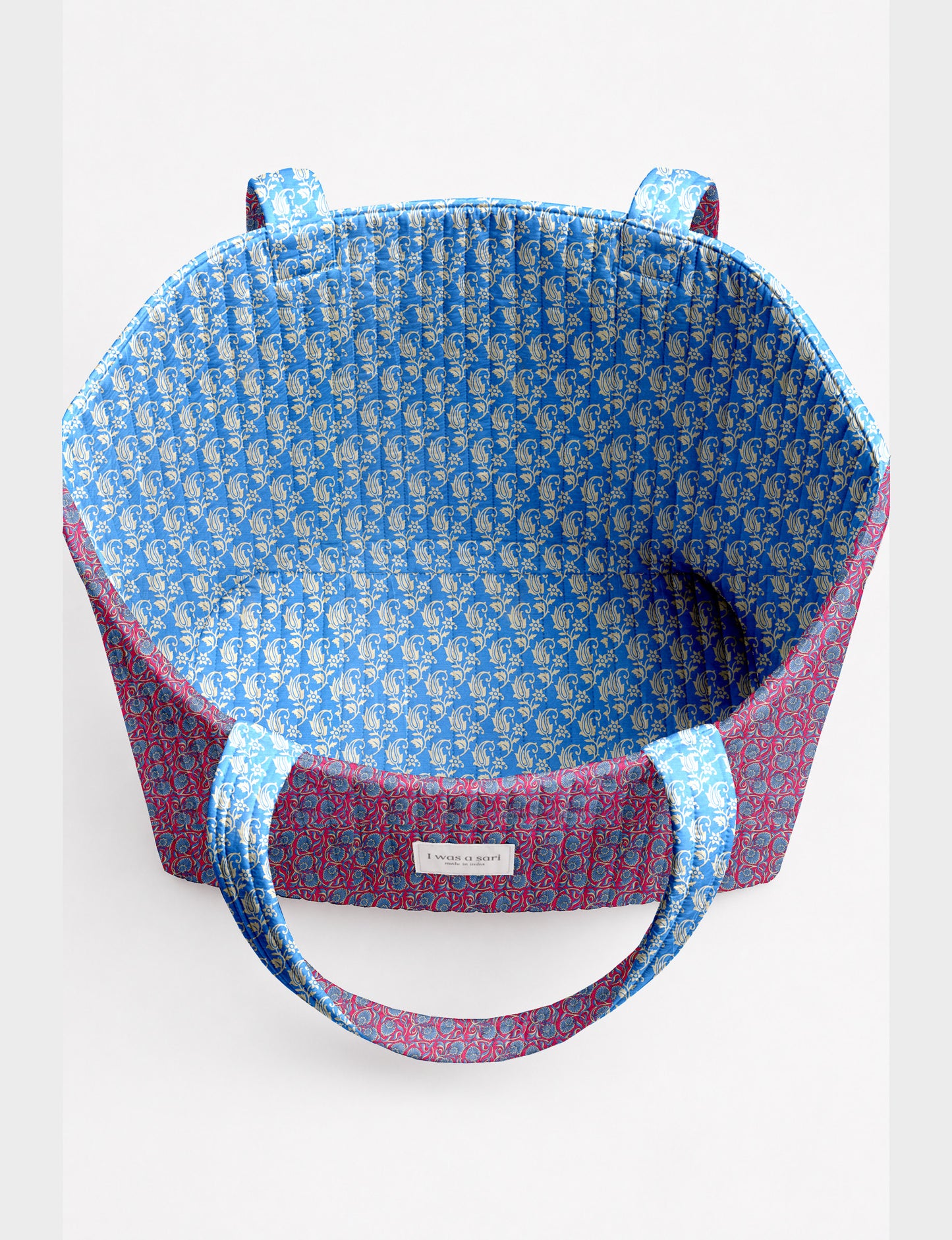 Quilted beach bag with yellow tropical exterior and red patterned interior, shown from top view with handles visible
