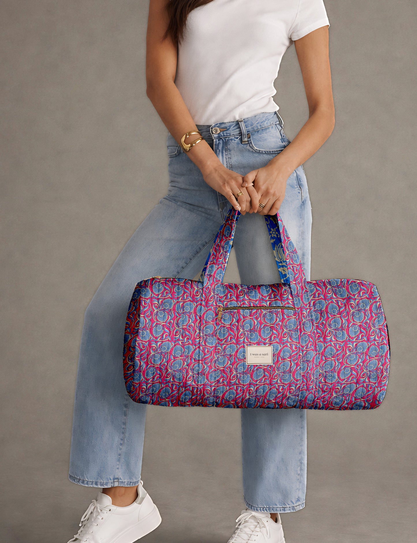 Brown paisley quilted bowling bag with front zipper pocket, held by person wearing white shirt and light blue jeans